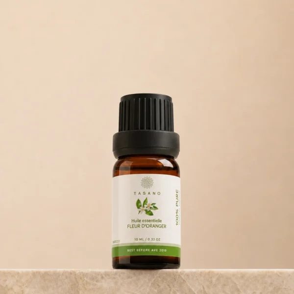 TASANO Orange Blossom Essential Oil 10 ml bottle on beige marble pedestal, Moroccan aromatherapy oil in amber glass. TASANO Orange Blossom Essential Oil 10 ml bottle on beige marble pedestal, Moroccan aromatherapy oil in amber glass.