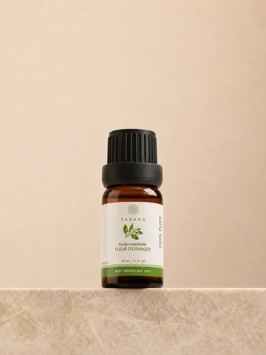 TASANO Orange Blossom Essential Oil 10 ml bottle on beige marble pedestal, Moroccan aromatherapy oil in amber glass.