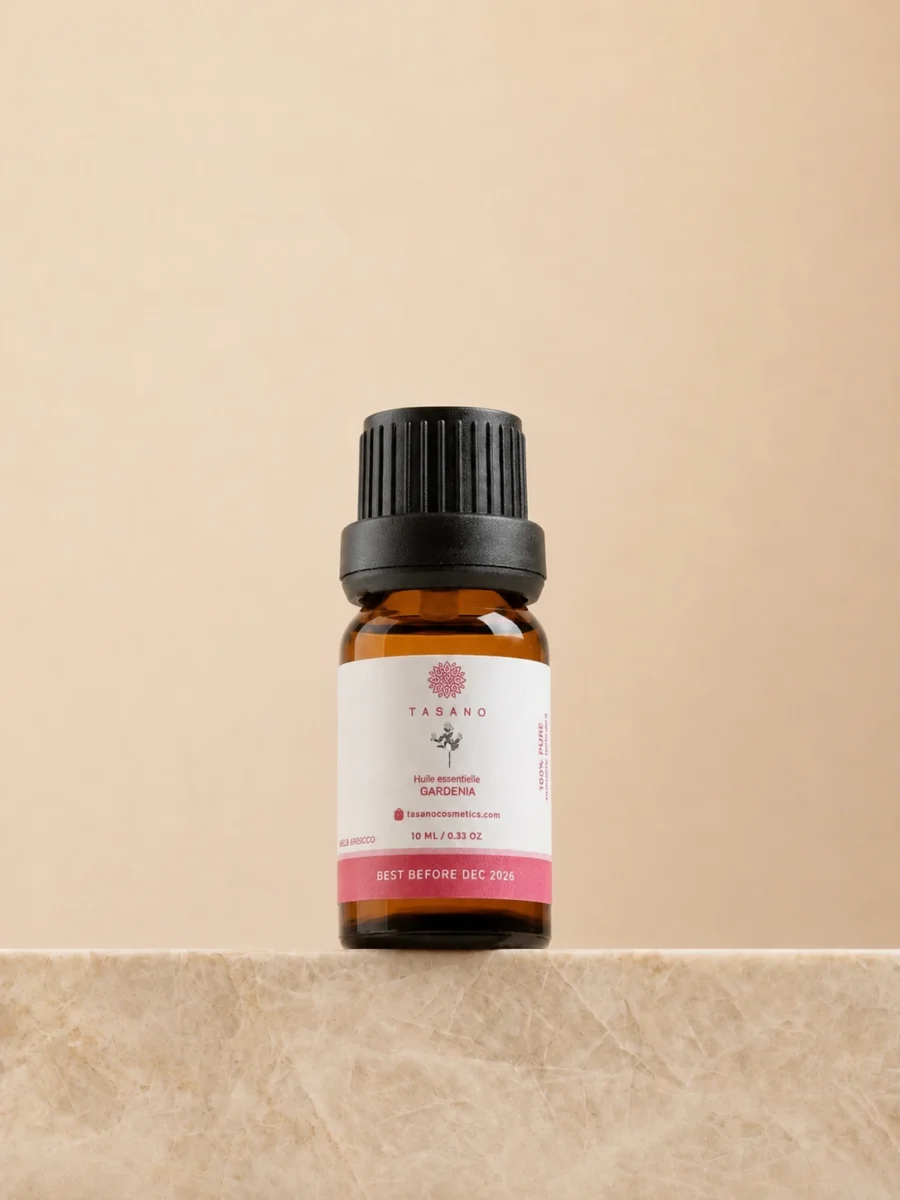 TASANO Gardenia Essential Oil 10 ml bottle on beige marble pedestal, Moroccan aromatherapy oil in amber glass.