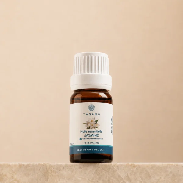 TASANO Jasmine Essential Oil 10 ml bottle on beige marble pedestal, Moroccan aromatherapy oil in amber glass. TASANO Jasmine Essential Oil 10 ml bottle on beige marble pedestal, Moroccan aromatherapy oil in amber glass.