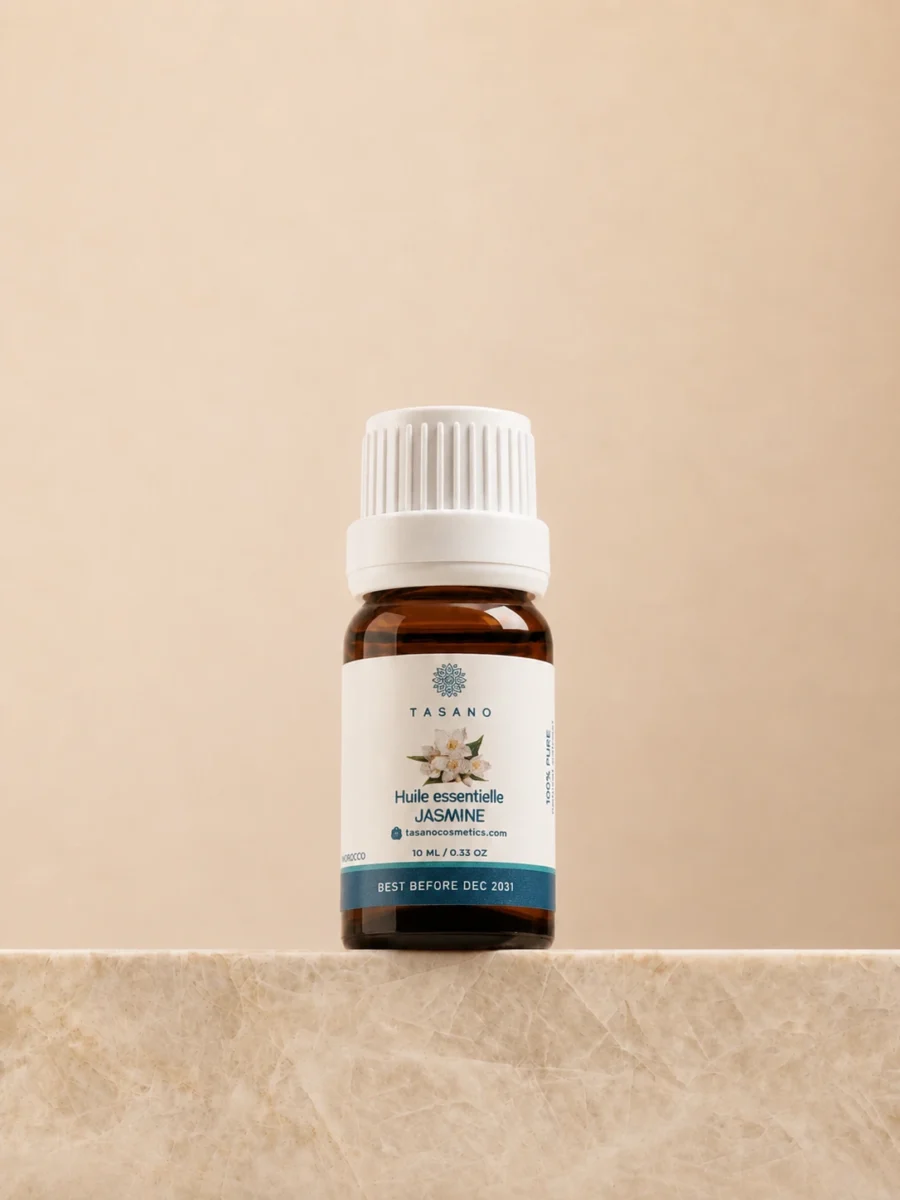 TASANO Jasmine Essential Oil 10 ml bottle on beige marble pedestal, Moroccan aromatherapy oil in amber glass.