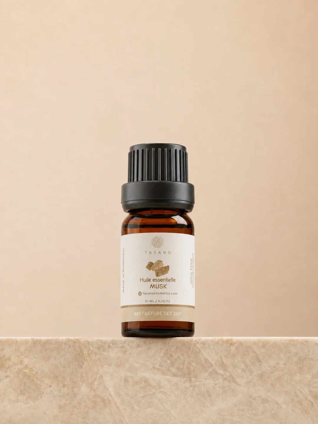 TASANO Musk Essential Oil 10 ml bottle on beige marble pedestal, Moroccan aromatherapy oil in amber glass.