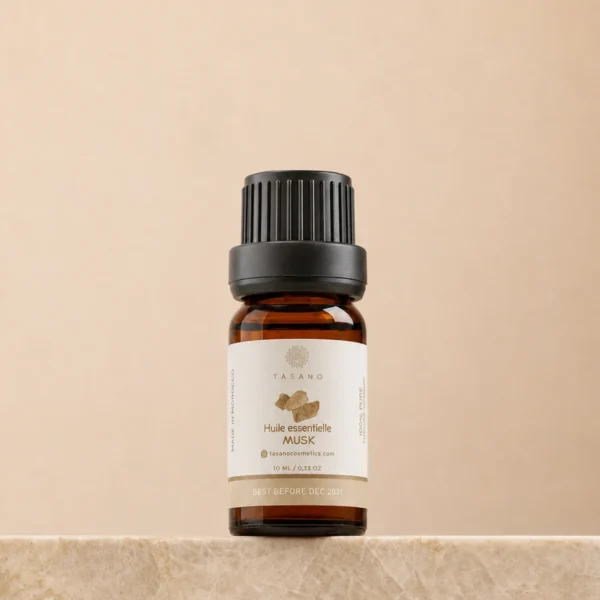 TASANO Musk Essential Oil 10 ml bottle on beige marble pedestal, Moroccan aromatherapy oil in amber glass.