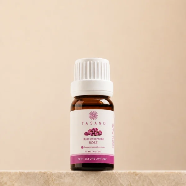 TASANO Rose Essential Oil 10 ml bottle on beige marble pedestal, Moroccan aromatherapy oil in amber glass.