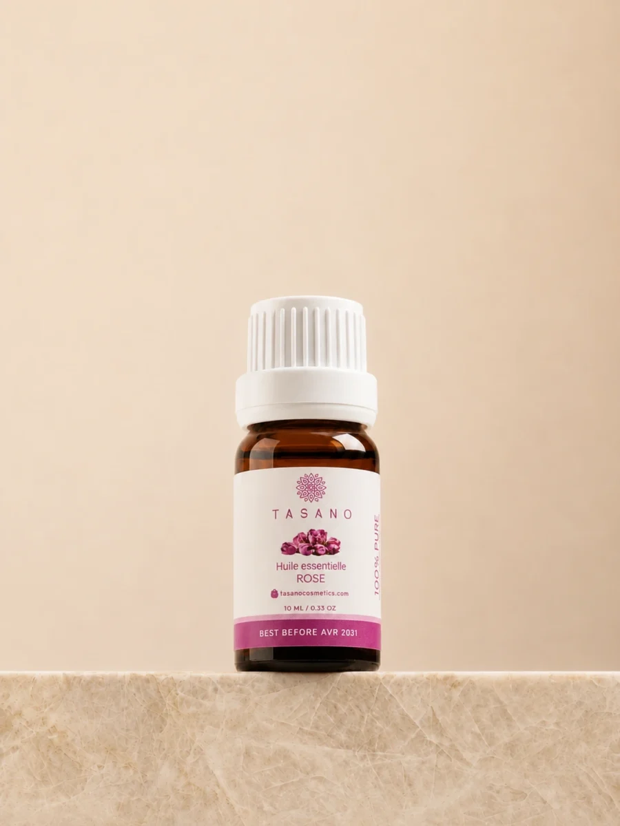 TASANO Rose Essential Oil 10 ml bottle on beige marble pedestal, Moroccan aromatherapy oil in amber glass.