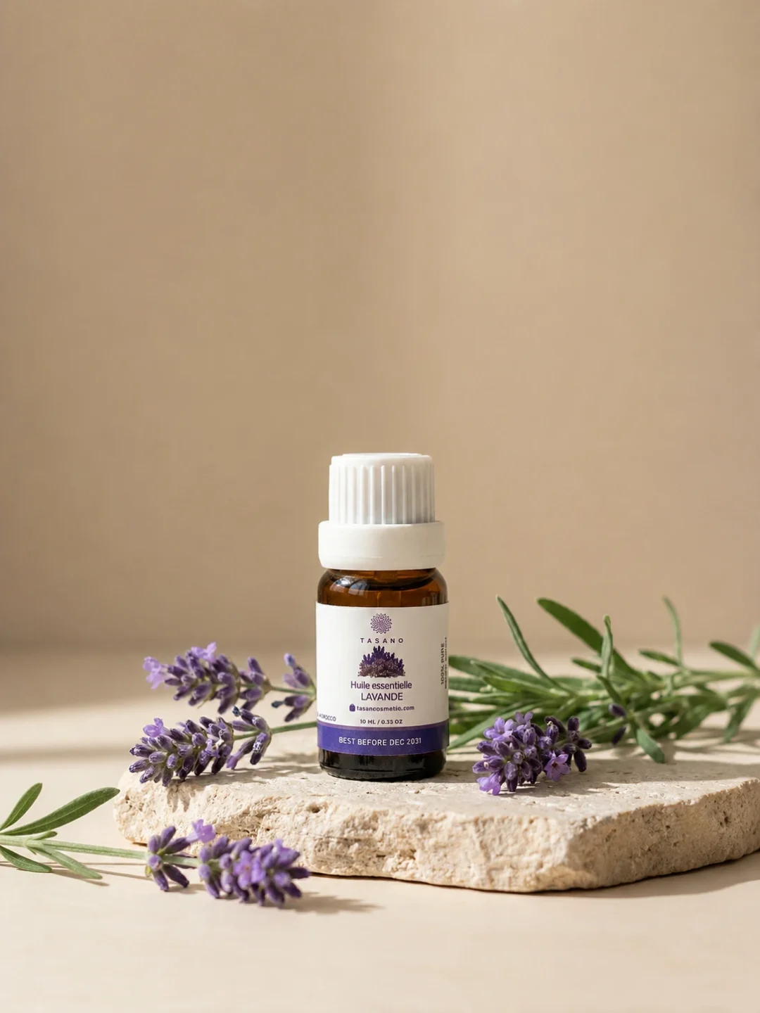 TASANO Lavender Essential Oil styled with fresh lavender, pale yellow oil drops, silk fabric, and beige stone.