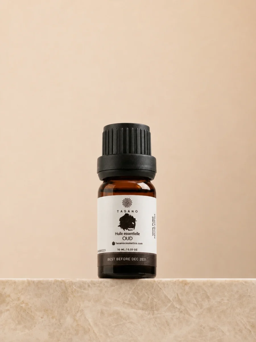 TASANO Oud Essential Oil 10 ml bottle on beige marble pedestal, Moroccan aromatherapy oil in amber glass.
